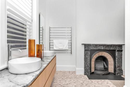 ein Badezimmer mit Waschbecken und Kamin in der Unterkunft The BeBe on Gover - Heritage Gem in North Adelaide in North Adelaide