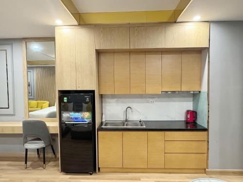a kitchen with a sink and a black refrigerator at Seafront Apartment TMS Quy Nhơn in Quy Nhon