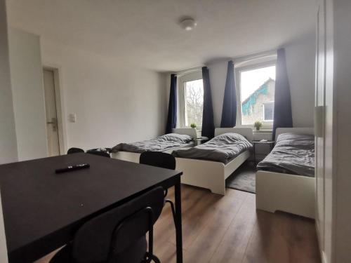 a room with two beds and a table with chairs at Apartmenthaus in Rüdersdorf in Rüdersdorf