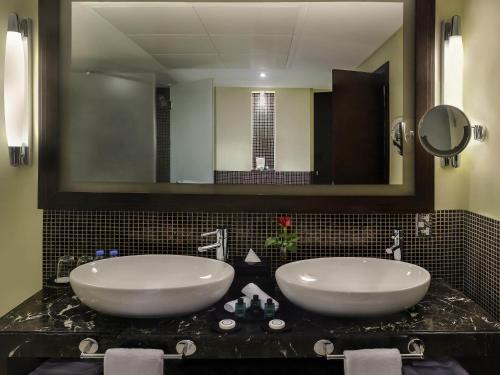 a bathroom with two sinks and a large mirror at Sofitel Al Khobar The Corniche in Al Khobar