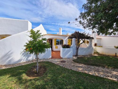 a white house with a tree in the yard at Aldeia do Golf - Vila I8 in Vilamoura
