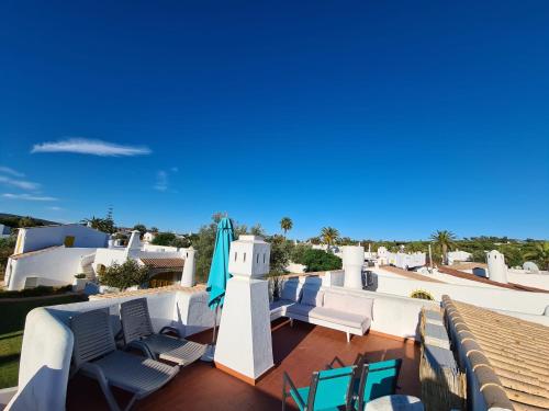 a balcony with chairs and a blue umbrella and a building at Aldeia do Golf - Vila I8 in Vilamoura