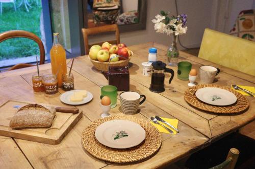une table en bois avec des assiettes de nourriture et une corbeille de fruits dans l'établissement Perche King's Bedroom in MaisonNomadeChic, à Cour-Maugis-sur-Huisne