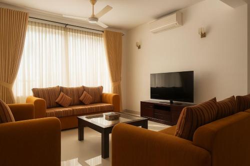 a living room with couches and a flat screen tv at Unique Towers Luxury Boutique Suites in Colombo