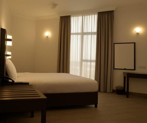 a hotel room with a bed and a window at Garden City Hotel Dubai in Dubai