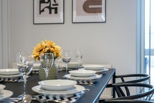 a black table with plates and glasses and a vase with flowers at Balfour House - Air Host & Stay - Sleeps 8, free parking in Litherland