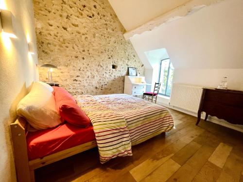 a bedroom with a bed in a room with a stone wall at Maison Nomade Perche - MaisonNomadeChic in Cour-Maugis-sur-Huisne
