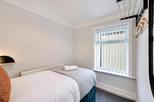 a white bedroom with a bed and a window at Balfour House - Air Host & Stay - Sleeps 8, free parking in Litherland
