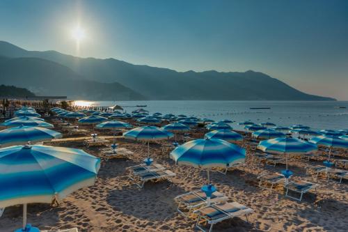 a group of blue umbrellas and chairs on a beach at U-NIGHT Hostel Budva in Budva