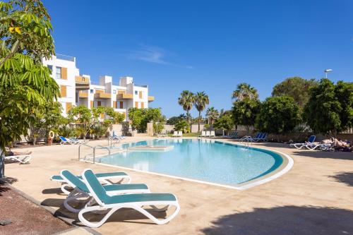 a swimming pool with lounge chairs and a resort at Seafront Penthouse in El Medano in El Médano