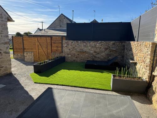 a yard with green grass and a stone wall at La Grange in Savenay