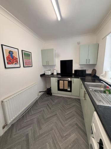 a kitchen with white cabinets and a counter top at ResiLets Taylor House in Bebside
