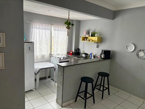 a small kitchen with a counter and two stools at Bertholi Beira-Mar in Serra