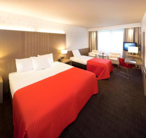 a hotel room with two beds with red sheets at Van der Valk Hotel de Bilt-Utrecht in De Bilt