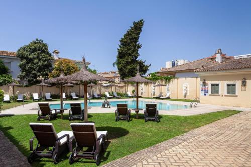 a group of chairs and umbrellas next to a pool at Villa Jerez in Jerez de la Frontera