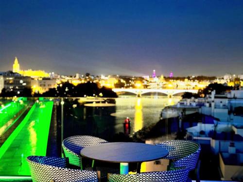 a table and chairs on a balcony with a view of a river at Ribera de Triana Hotel in Seville