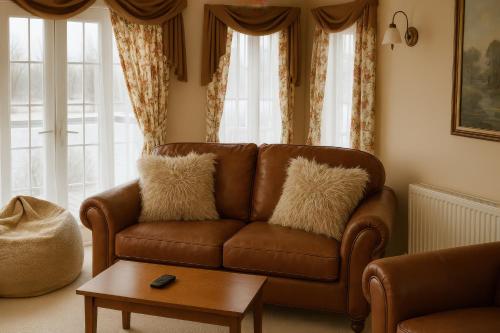 un divano in pelle marrone in un soggiorno con finestre di Combe Haven Holiday Park - Holiday Accommodation 12122 a Hollington