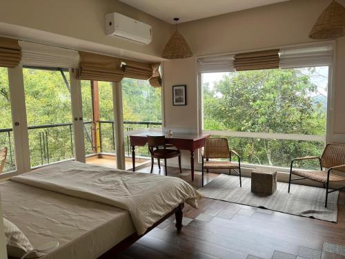 une chambre avec un lit, un bureau et des fenêtres dans l'établissement Luxury Villa in Wayanad Hills with Private Garden, à Wayanad