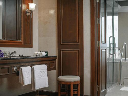 a bathroom with a shower and a sink and a stool at Sofitel Phnom Penh Phokeethra in Phnom Penh