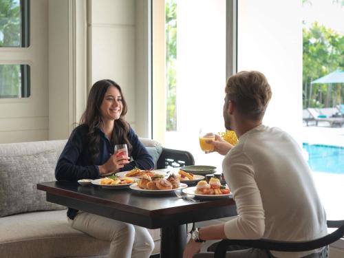 a man and woman sitting at a table with plates of food at Sofitel Phnom Penh Phokeethra in Phnom Penh