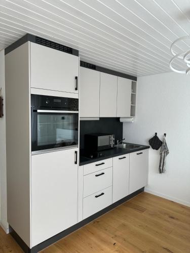 a kitchen with white cabinets and a sink at Gästehaus MaryVitty, zentrale zwischen Aarau und Olten, gut verbunden in Schönenwerd