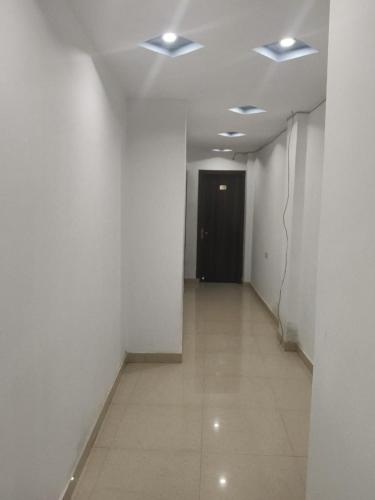a hallway with white walls and a black door at Flagship Hotel Shivaay Inn in Kānpur