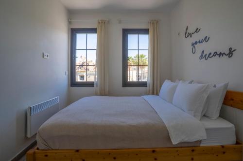 a bedroom with a large bed and two windows at Naro Suites Çeşme Marina in Çeşme
