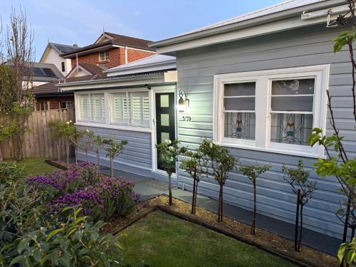 a blue house with trees in the front yard at Seaside Village Cottage Charm in Shellharbour