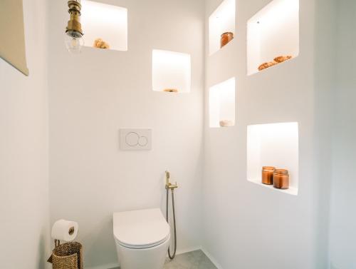 a white bathroom with a toilet and some shelves at Turquoise in Platis Yialos Sifnos