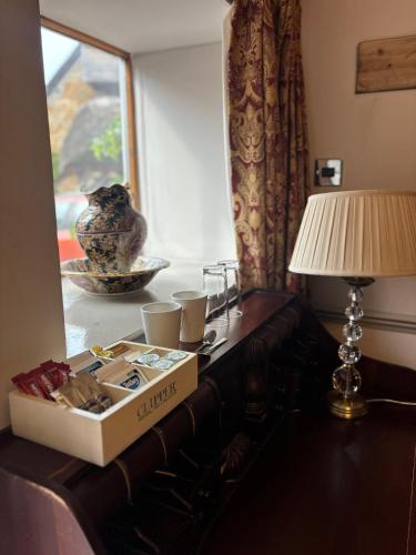 a box on a table with a lamp and a window at The George Hotel in Castle Cary