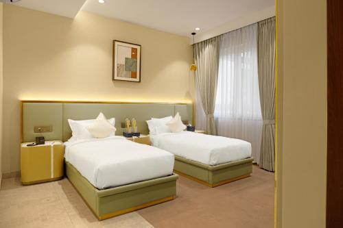 a hotel room with two beds and a window at Quad Hotels Hyderabad in Hyderabad