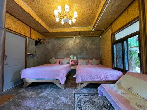 a bedroom with two beds and a chandelier at สบายดีแม่กลางหลวง in Ban Sop Mae Klang