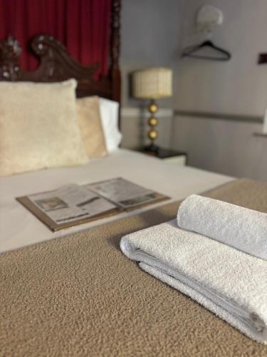 a bed with two towels sitting on top of it at The George Hotel in Castle Cary