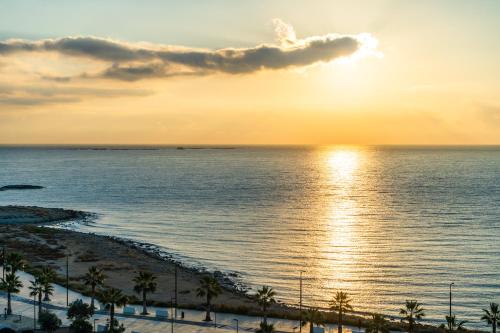 a sunset over a beach with palm trees and the ocean at Vistamar Hotel Luxury Wellness By DLV -Adults Only- in Villajoyosa
