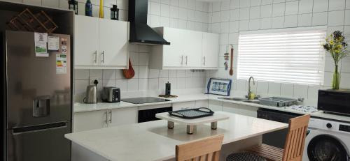 a kitchen with white cabinets and a table in it at Dolfyn201 La Mer in Hartenbos