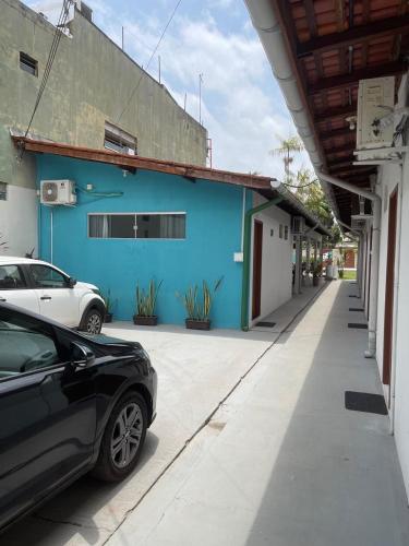 a blue building with cars parked on a street at Vila Suítes in Barcarena
