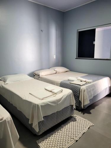 a room with two beds and a flat screen tv at POUSADA ALÉM-K in Riachão