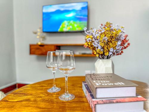two wine glasses sitting on a table with a book at The Dar es Salaam Stay Nyumbani -1BR Urban Retreat in Dar es Salaam
