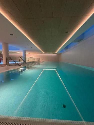 a large swimming pool with blue water in a building at PINEA Apartments Pobierowo z niesamowitym widokiem na morze oraz jacuzzi w wybranych apartamentach in Pobierowo
