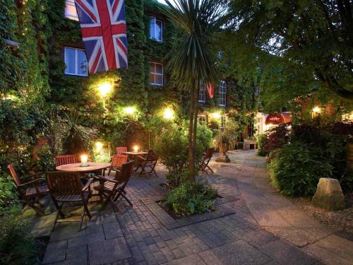 a patio with a table and chairs and a flag at Mercure Salisbury White Hart Hotel & Apartments in Salisbury