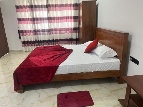 a bedroom with a bed with a red blanket on it at Gateway terrace CMB Airport katunayake in Seeduwa