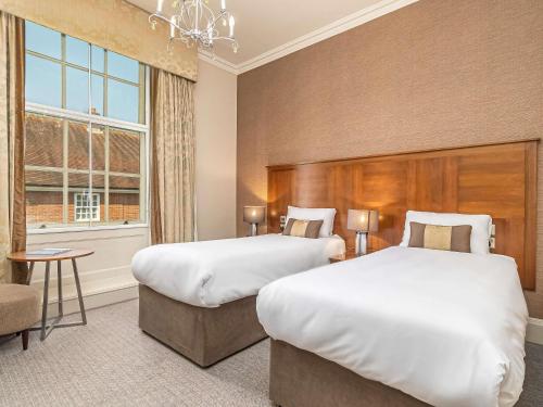 a hotel room with two beds and a window at Mercure Salisbury White Hart Hotel & Apartments in Salisbury