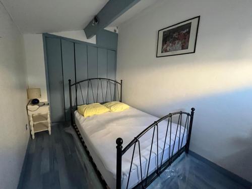 sypialnia z łóżkiem z białą pościelą i żółtymi poduszkami w obiekcie La MAISON BLEUE w mieście Gruissan