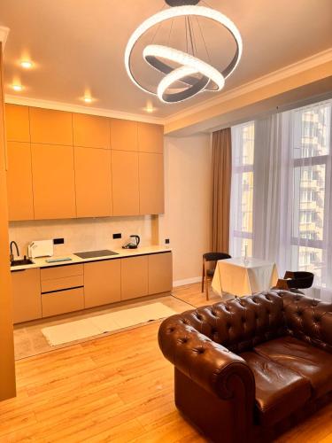 a living room with a leather couch and a kitchen at Premium Delux Astana in Zhezdi