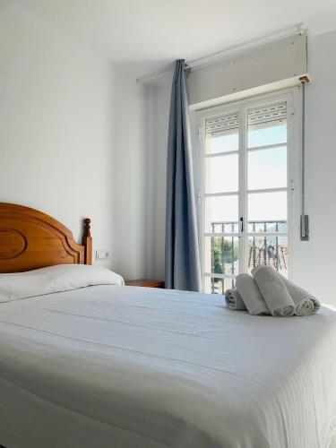 a bedroom with a large white bed with a window at Playa Golf Apartamentos con Piscina in Benalmádena