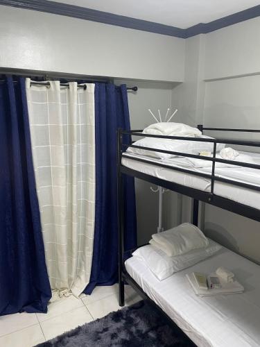 a room with two bunk beds with blue curtains at Affordable 2BR Near Airport with WiFi, Netflix and Pool in Mactan