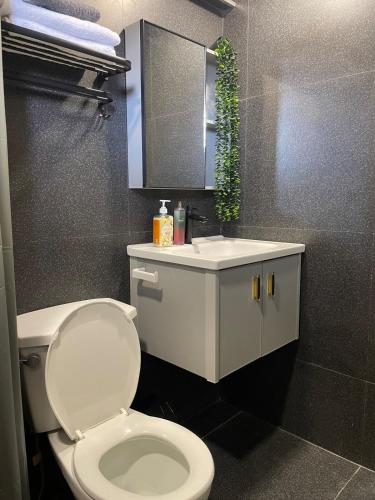 a bathroom with a white toilet and a sink at Affordable 2BR Near Airport with WiFi, Netflix and Pool in Mactan