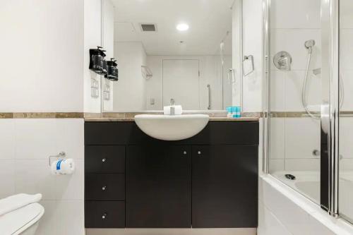 a bathroom with a white sink and a shower at KozyGuru | Haymarket | Stylish City Studio in Sydney
