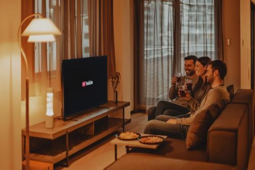 three men sitting in a living room watching television at Hazama in Tokyo