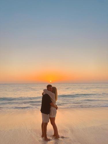 a man and woman hugging on the beach at sunset at Royal Mandarin Hotel & Resort in Pwani Mchangani